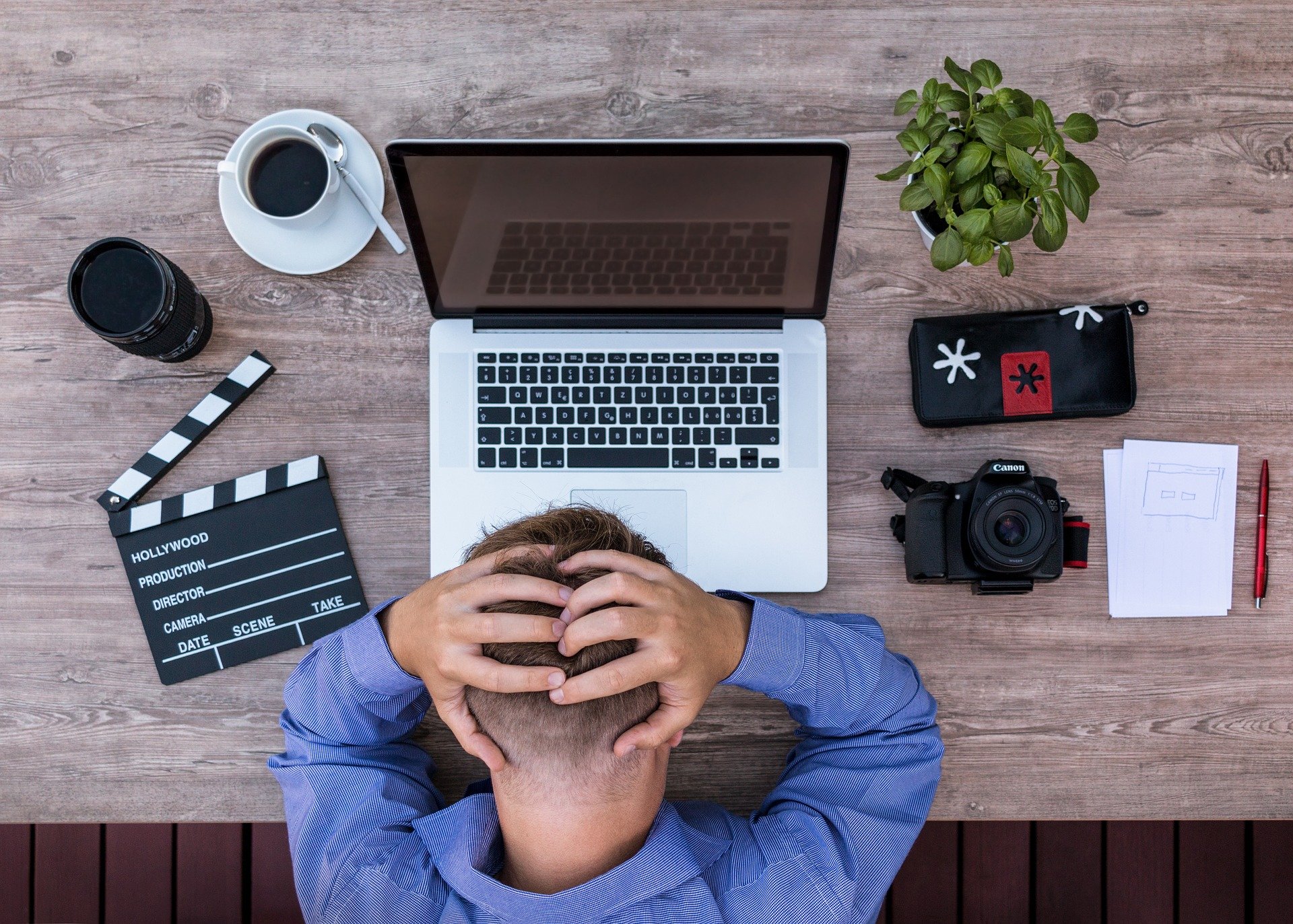 Mann vor Laptop mit zusammengeschlagenen Händen auf Kopf